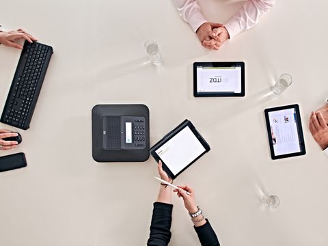 Tablets, Tastatur, Maus und mehrere Arme von Peronen auf einem Tisch