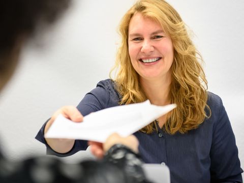 zwei Mitarbeiterinnen, die sich Dokumente überreichen