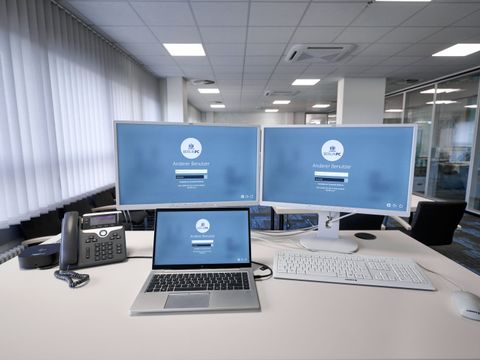IKT-Arbeitsplatz auf Schreibtisch mit zwei Monitoren, Laptop, Telefon, Tastatur und Maus