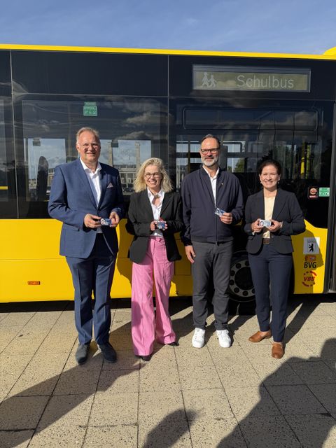 Projektbeteiligte mit digitalem Schülerausweis in der Hand, stehen vor einem Bus der BVG