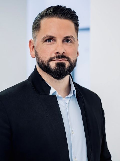 Porträtfoto von Maximilian Krause, Abteilungsleiter Personal im ITDZ Berlin. Er trägt ein hellblaues Hemd und ein dunkles Sakko und blickt vor hellem Hintergrund in die Kamera.