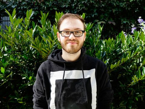 Ein lächelnder Mitarbeiter des ITDZ-Berlin steht vor einem pflanzen Hintergrund.