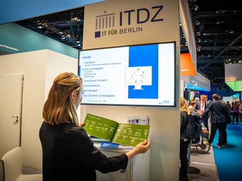 Frau am ITDZ Stand, schaut in Broschüre