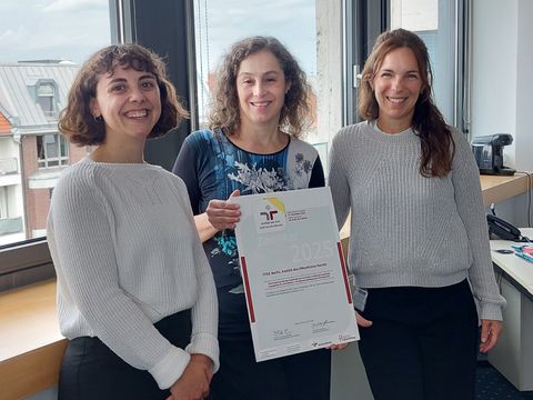 Drei Frauen, in der Mitte hält Maria Borelli Zertifikat