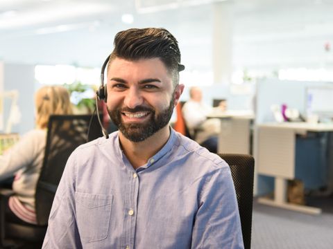 Person mit Head Set lacht freundlich in die Kamera