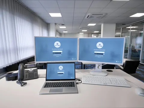 IKT-Arbeitsplatz auf Schreibtisch mit zwei Monitoren, Laptop, Telefon, Tastatur und Maus