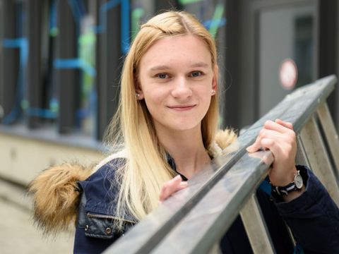 Eine lächelndee Mitarbeiterin des ITDZ-Berlin trägt eine Leiter auf ihrer Schulter.