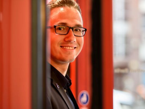 Ein lächelnder Mitarbeiter des ITDZ-Berlin steht in einem Eingang eines ITDZ-Berlin Gebäude