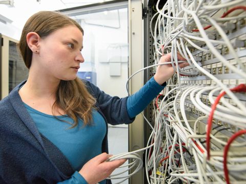 Mitarbeiterin, die an einem Serverschrank arbeitet