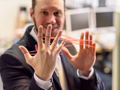 Ein Mann hält Fäden-Netz zwischen den Fingern