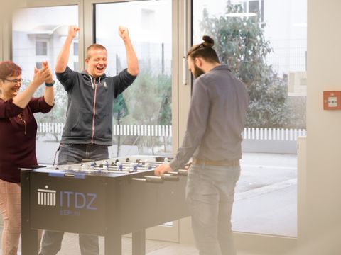 3 Mitarbeitenden an einem Kickertisch