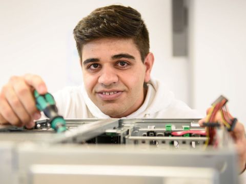 "Ahmad" arbeitet konzentriert an einem Computer Gehäuse.