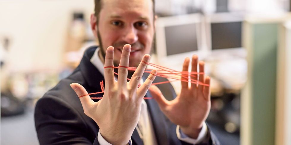 Ein Mann hält Fäden-Netz zwischen den Fingern