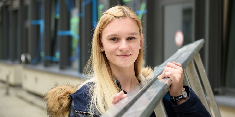 Eine lächelndee Mitarbeiterin des ITDZ-Berlin trägt eine Leiter auf ihrer Schulter.