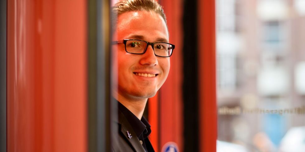Ein lächelnder Mitarbeiter des ITDZ-Berlin steht in einem Eingang eines ITDZ-Berlin Gebäude