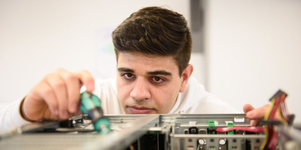 "Ahmad" arbeitet konzentriert an einem Computer Gehäuse.
