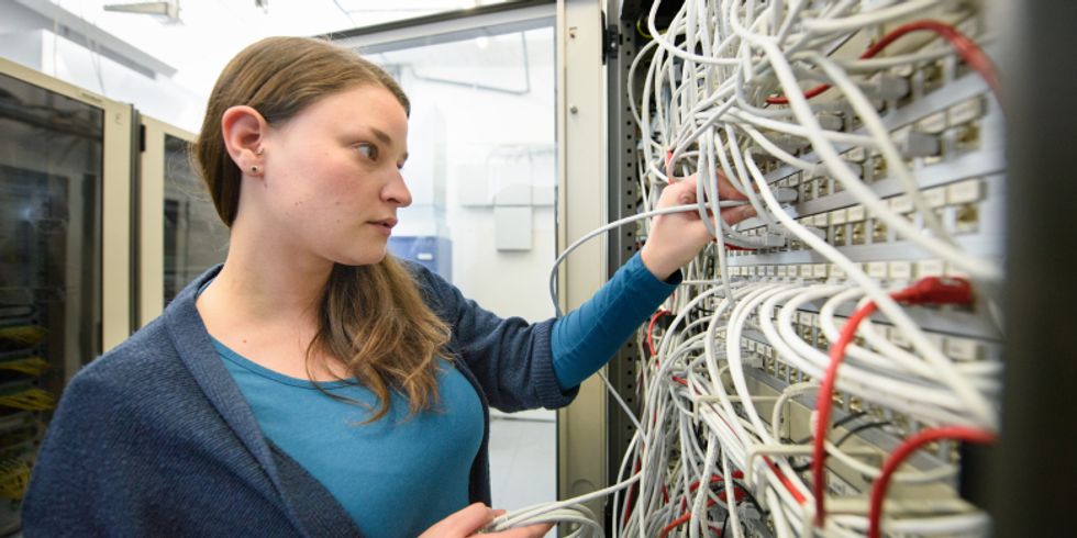 Mitarbeiterin, die an einem Serverschrank arbeitet