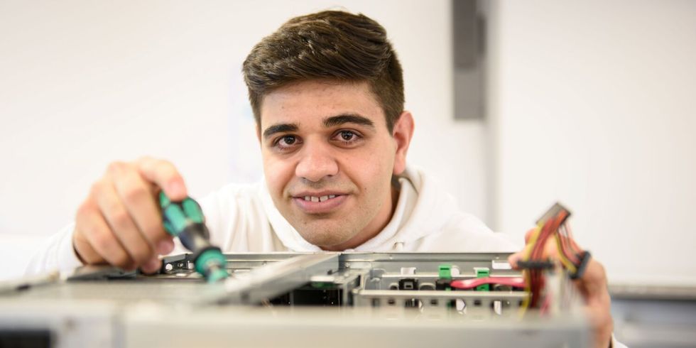 "Ahmad" arbeitet konzentriert an einem Computer Gehäuse.