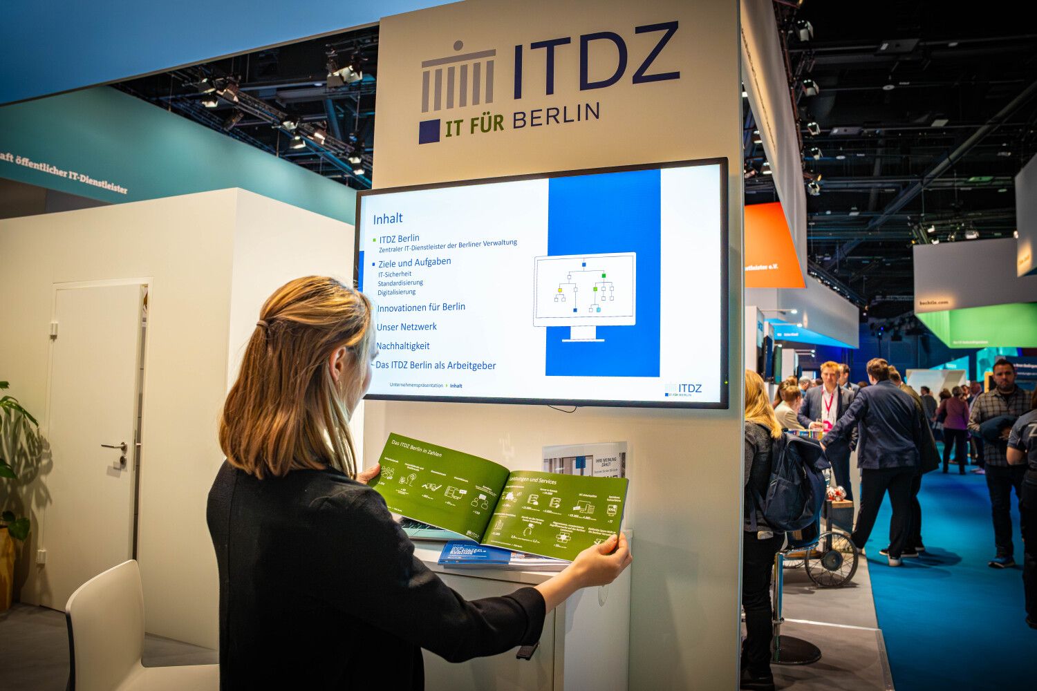 Frau am ITDZ Stand, schaut in Broschüre