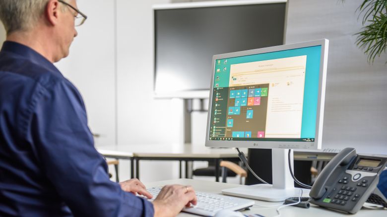 Person sitzt mit dem Rücken zur Kamera vor einem Monitor