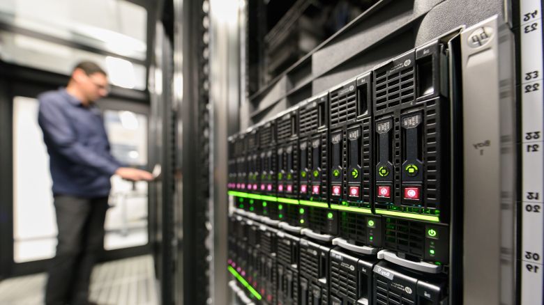 Person steht verschwommen im Hintergrund vor Server Schränken