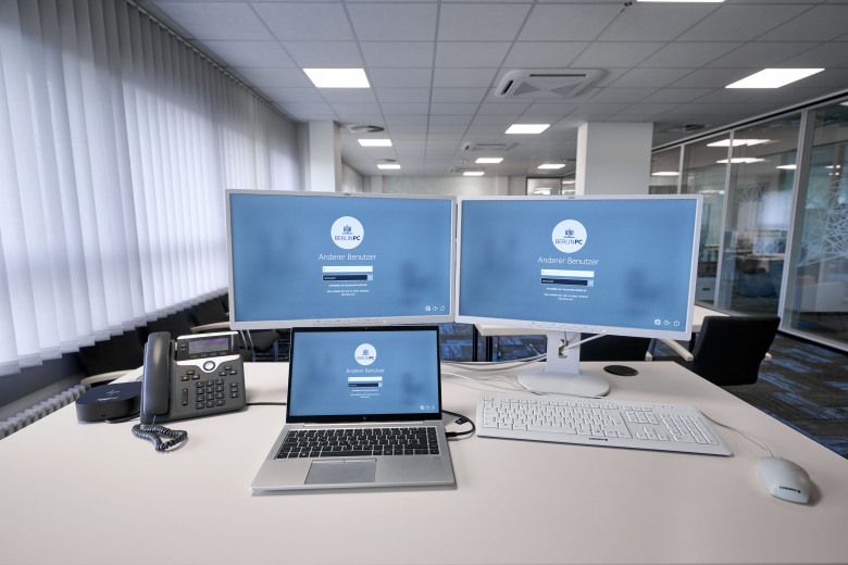 IKT-Arbeitsplatz auf Schreibtisch mit zwei Monitoren, Laptop, Telefon, Tastatur und Maus