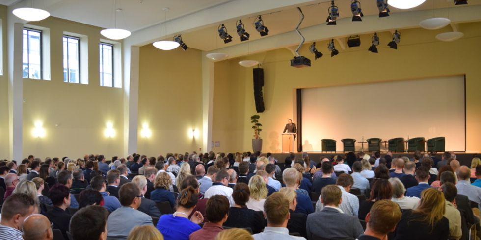 Ein Halle von Menschen mit einer Bühne im Hintergrund