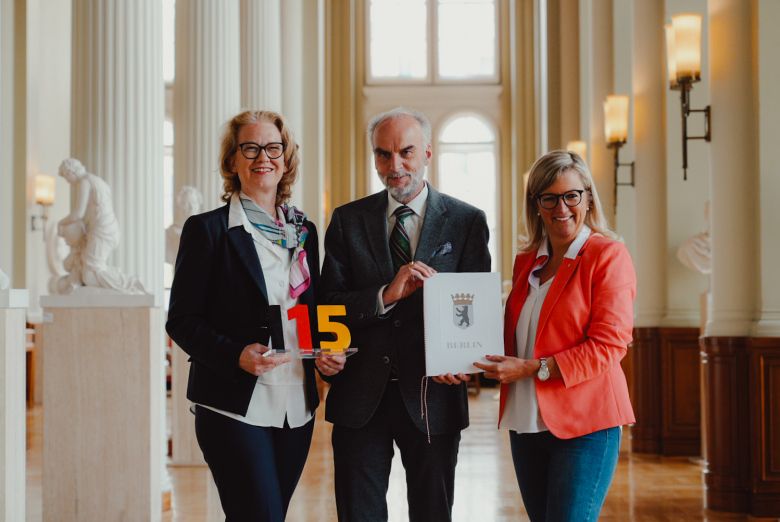 Martina Klement, Anne Lolas und Markus Grünwald halten Dokument und 115-Symbol in den Händen