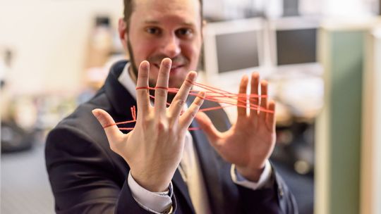 Ein Mann hält Fäden-Netz zwischen den Fingern