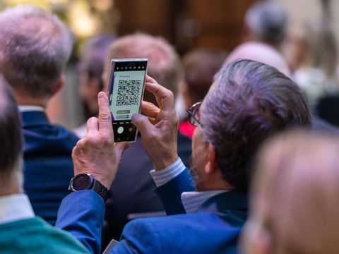 Mann im Publikum scant QR-Code mit seinem Handy