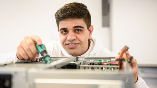 "Ahmad" arbeitet konzentriert an einem Computer Gehäuse.