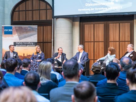 Menschen diskutieren auf einem Podium vor Publikum
