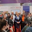 Bildvergrößerung: große Gruppe von Menschen, in der Mitte die Berliner Bürgermeisterin, steht auf dem Smart City Stand und lächelt in die Kamera