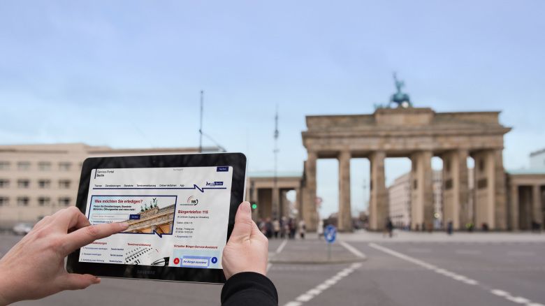 Tablet zeigt das Brandenburger Tor, welches im Hintergrund verschwommen steht
