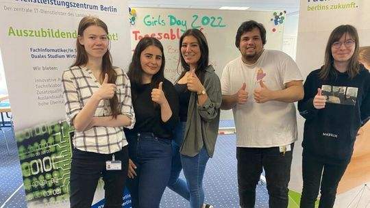 Zu sehen sind 5 junge Menschen die ihre Daumen hoch machen und vor einer Tafel mit der Aufschrift Girlsday 2022 stehen